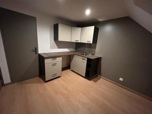 Elle comprend une petite cuisine avec des placards blancs et du parquet. dans l'établissement L Appart 63 - Arnage - circuit 24, à Arnage