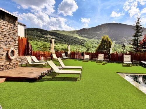 a lawn with chairs and a table and a fence at Aparthotel Siente Boí & SPA in Pla de l'Ermita