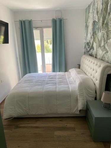 a bedroom with a white bed with blue curtains and a window at Cassino - Appartamento Green - Parco del Gari in Cassino