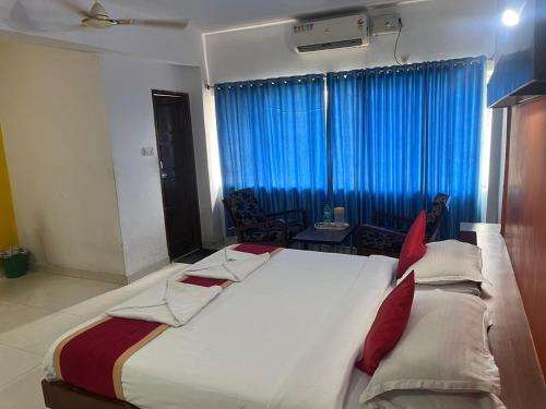 a large bed in a room with blue curtains at Hotel sai arcade in Bengaluru