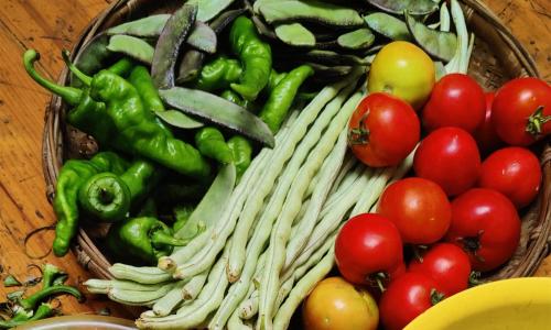 a basket of vegetables on a table with tomatoes at Zhangjiajie Jijiehao Inn in Zhangjiajie