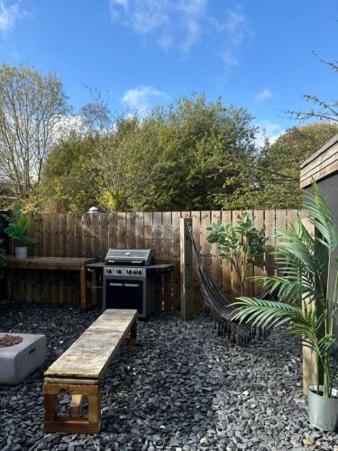 a backyard with a stove and a bench and a fence at The Pinewood Cabin With Firepit & BBQ in Ringwood