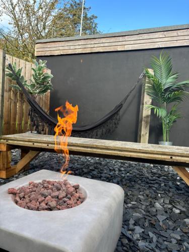 a fire pit in front of a bench and a hammock at The Pinewood Cabin With Firepit & BBQ in Ringwood