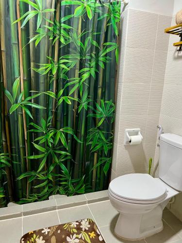 a bathroom with a toilet with a bamboo shower curtain at H2G Mesavirre Garden Residence in Bacolod