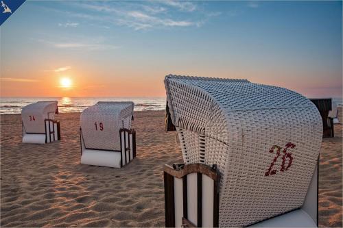 a group of chairs on the beach at sunset at Apartment Nähstube in Bansin
