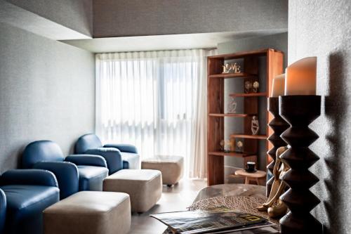 a living room with blue chairs and a window at Roxon Urban Ramat Gan in Ramat Gan