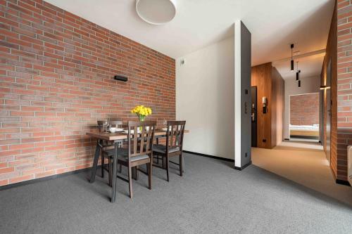 a dining room with a brick wall and a table and chairs at Apartamenty Pod Grojcem - Dream Apart in Żywiec
