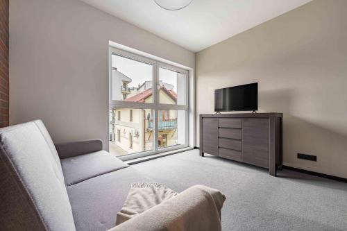 a living room with a couch and a tv and a window at Apartamenty Pod Grojcem - Dream Apart in Żywiec