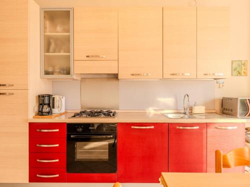 a kitchen with red cabinets and a stove top oven at Apartment Paníco by Interhome in Dorio