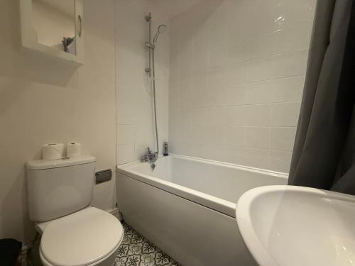 a bathroom with a toilet and a tub and a sink at Central 2 bed flat with off street-parking in Bristol