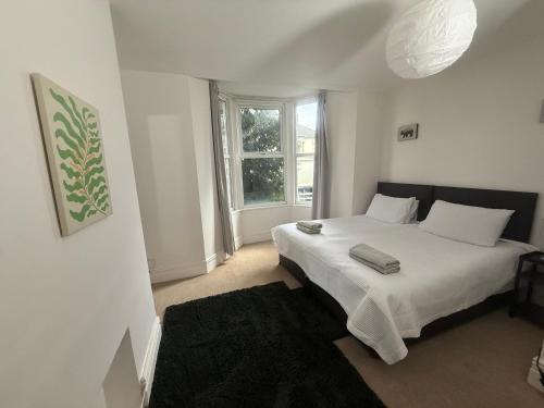 a bedroom with a white bed and a window at Central 2 bed flat with off street-parking in Bristol