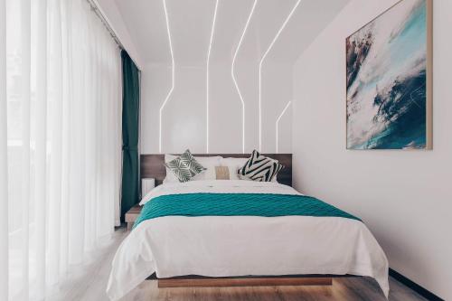 a bedroom with a large bed with white walls at Dali Mermaid Seascape Resort Hotel in Dali