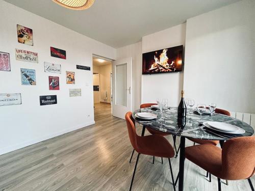 une salle à manger avec une table et des chaises en verre dans l'établissement Champagne T3 avec balcon et garage vue basilique, à Reims