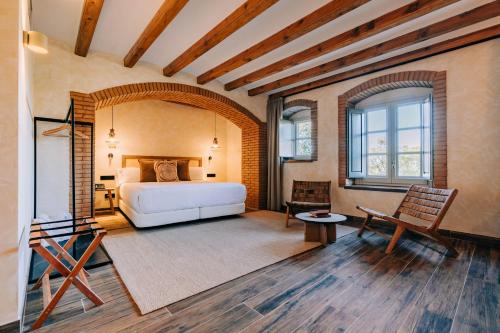 a bedroom with a bed and a chair in a room at Gran Claustre Boutique Hotel in Altafulla