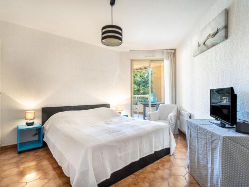 a bedroom with a white bed and a television at Apartment Les Regates-1 by Interhome in Hyères