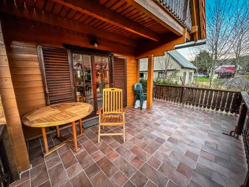 a wooden table and chair on a patio at Rustikalna kuća Snowdrop s kaminom u Begovom Razdolju, Gorski kotar in Begovo Razdolje