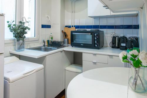 - une cuisine blanche avec un four micro-ondes et un évier dans l'établissement 4 Guests Apt Jardin des Plantes, à Paris