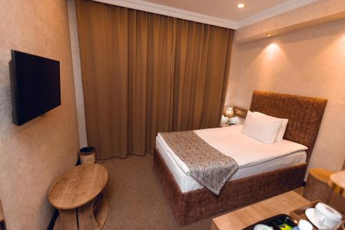 a hotel room with a bed and a television at Baku Hotel Ganja in Ganja