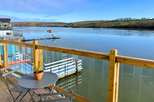 a table on a balcony with a view of a river at Estuary's Rest Studio Apartment at Galwad Y Mor in Cardigan