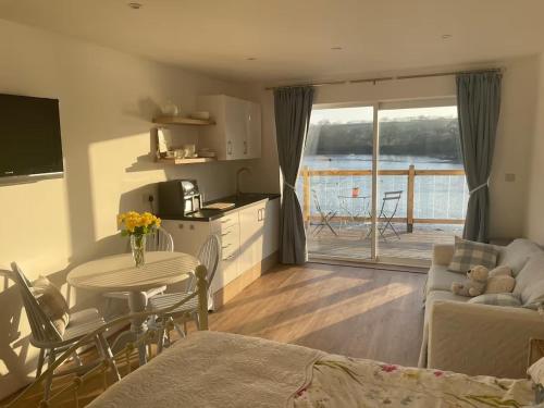 Una sala de estar con cocina y una mesa con sillas. en Estuary's Rest Studio Apartment at Galwad Y Mor, en Cardigan
