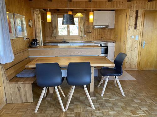 a kitchen with a wooden table and two blue chairs at Chalet Chalet Soldanella - BEL205 by Interhome in Bellwald