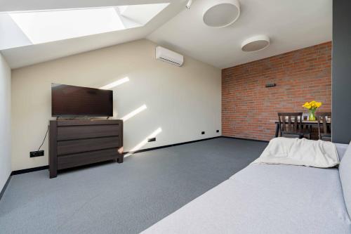 a bedroom with a flat screen tv and a brick wall at Apartamenty Pod Grojcem - Dream Apart in Żywiec