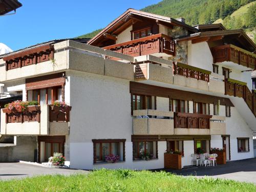 a large building with balconies and tables and chairs at Apartment Haus Quelle-1 by Interhome in Saas-Grund