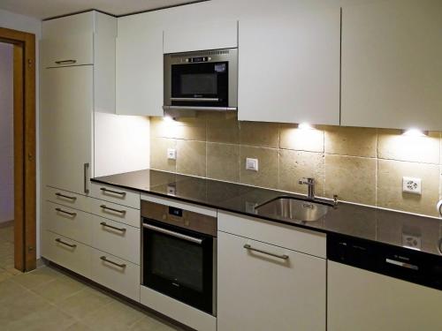 a kitchen with white cabinets and a sink and a microwave at Apartment Haus Quelle-5 by Interhome in Saas-Grund