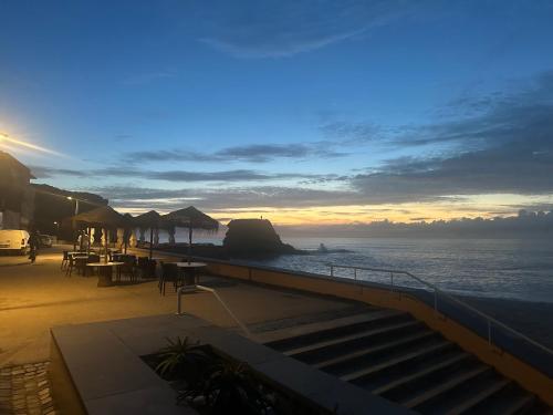 a sunset over the ocean with tables and chairs at Promar - Eco Beach & Spa Hotel in Maceira