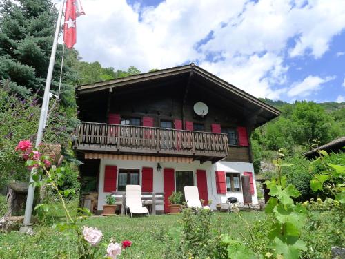 a house with a balcony and two white chairs at Chalet Chalet Walliserträumli - BET410 by Interhome in Grengiols