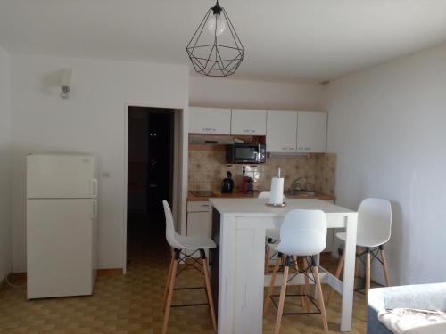 - une cuisine avec une table blanche et des chaises blanches dans l'établissement appartement confortable, à Sainte-Croix-de-Verdon