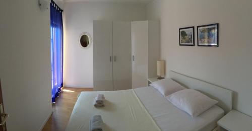 a white bedroom with a white bed and a window at Barižon Apartments in Tisno