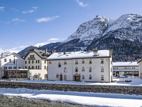 a large white building with snowy mountains in the background at Apartment Chesa Alossa by Interhome in La Punt-Chamues-ch