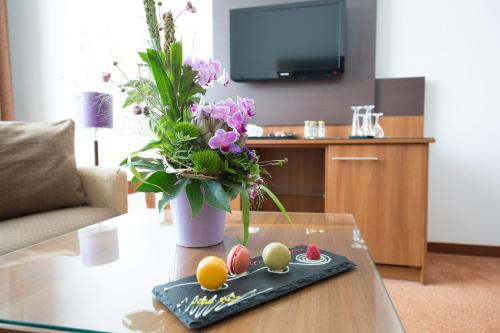 a living room with a table with a vase of flowers at Dorint Hotel am Dom Erfurt in Erfurt
