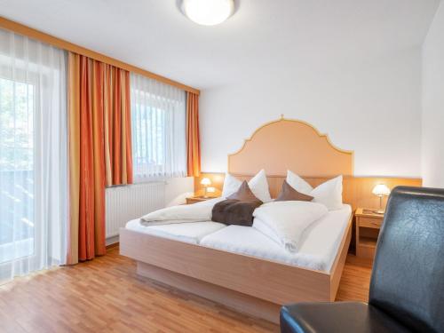 a bedroom with a large white bed with orange curtains at Apartment Rosa-9 by Interhome in Mayrhofen