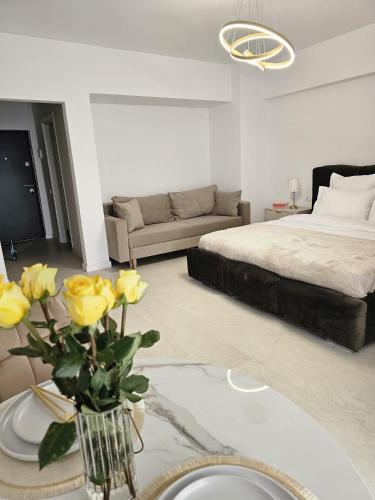 a living room with a bed and a vase with yellow roses at Studio 126 in Eforie Nord
