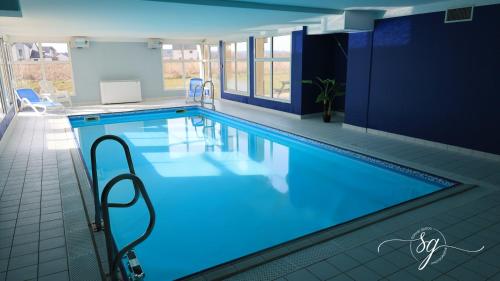 une grande piscine avec de l'eau bleue dans un immeuble dans l'établissement Le terrier du Green appartement, à Levernois