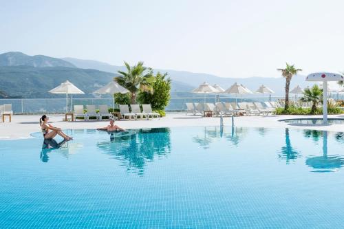 two women sitting in a swimming pool at a resort at Unique Residence Hotel Golf and Spa in Soke