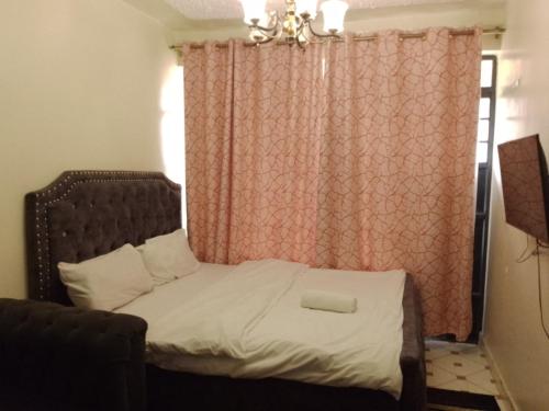a bedroom with a bed with a red curtain at Traveler's Staycation II in Rungiri