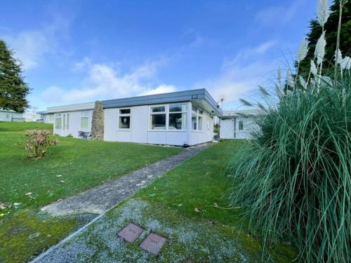 a white house with a grass yard at 2 bed chalet beaches nearby in Roch