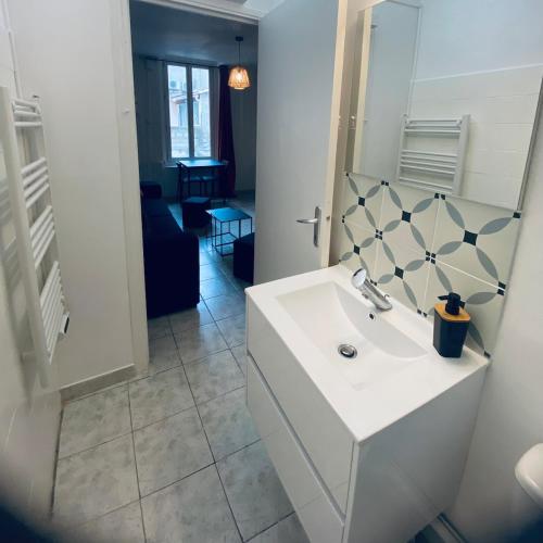 une salle de bain blanche avec un lavabo et un miroir dans l'établissement Meneau 3-Beziers Centre-Wifi-Tv Connectée, à Béziers