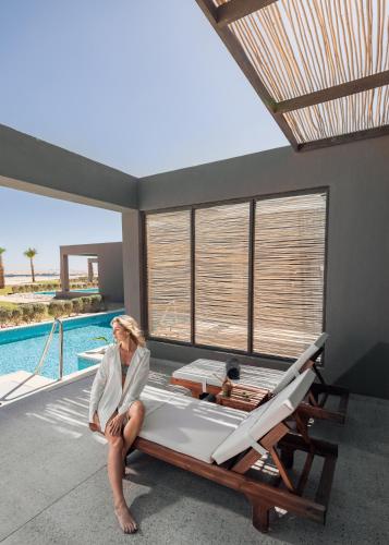 a woman sitting on a bed next to a pool at Sentido Naga Bay - Adults friendly in Hurghada