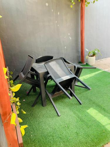 un patio con 3 sillas y una mesa sobre hierba en Lux-Villa, en Enugu