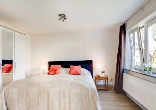 Un dormitorio blanco con una cama grande con almohadas rojas. en WS Ferienwohnung Meer, en Gelting