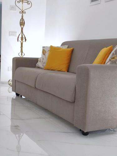 a grey couch with yellow pillows on top of it at LianHome b&b "Volte" in Lucera