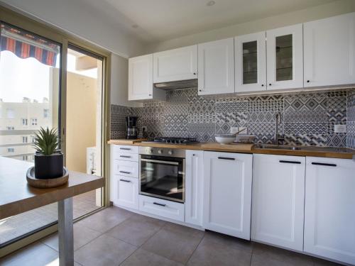 une cuisine blanche avec des armoires blanches et un évier dans l'établissement Apartment Cagnes Provencal by Interhome, à Cagnes-sur-Mer