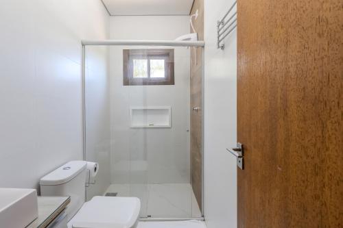a white bathroom with a toilet and a shower at Pousada Natribus Rosa in Praia do Rosa