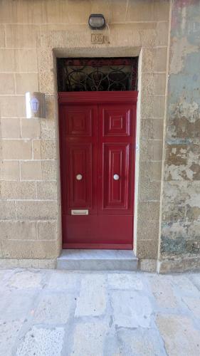 a red door on the side of a brick building at Valletta Authentic Apartment in Valletta
