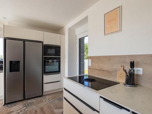 a kitchen with a stainless steel refrigerator and white cabinets at Holiday Home La Maison de Parrain by Interhome in Kerlouan