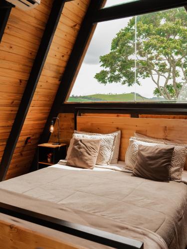 a bed in a room with a large window at Cabana Jequitibá in Maria da Fé